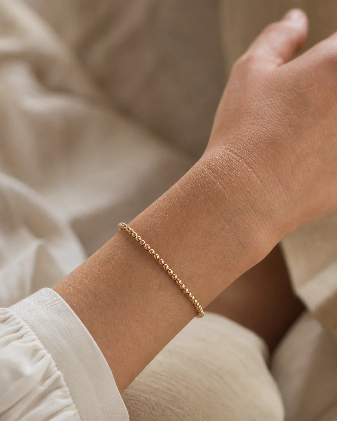 Pulsera de bolas en oro laminado y oro rosa puesta en la muñeca